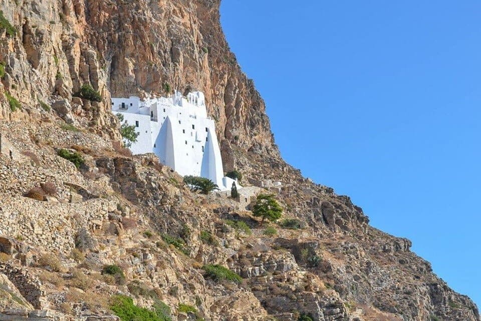 Amorgos Sends Message of Optimism Through Gastronomy - Gastronomy Tours view of church surrounded by rocks at Amorgos that Sends Message of Optimism Through Gastronomy