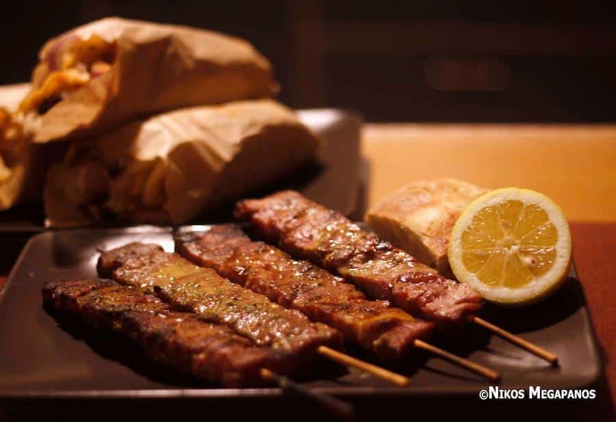 Thessaloniki, City of Gastronomy - Gastronomy Tours close-up of wooden sticks with cooked Greek souvlaki on plate and a half of lemon|