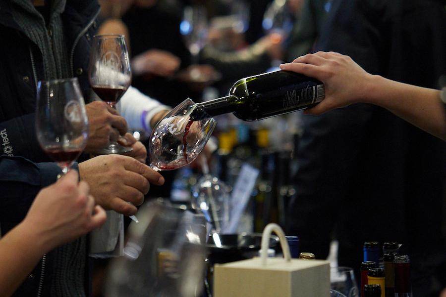 Peloponnese Wine Festival - Gastronomy Tours woman pouring wine in glasses from the bottle at PELOPONNESE WINE FESTIVAL