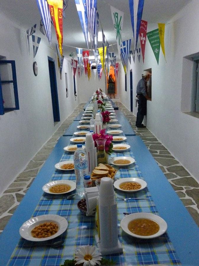 Sifnos, Festival of the Panagia of Chrisopigi - Gastronomy Tours long table with plates with revithada at church of Panagia of Chrisopigi - Gastronomy Tours