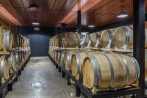 corridor of Callicounis Distilleries cellar with wooden barrels on top of each other on the both sides