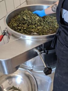 Close-up of a woman mixing dried herbs in a mixer at Rhoeco Fine Organic Goods laboratory