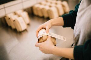 Close-up of a woman putting labels on paper packets of dried herbs at Rhoeco Fine Organic Goods laboratory