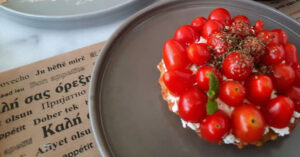 A picture of ntakos shows a Cretan dish consisting of a thick slice of barley rusk topped with chopped tomatoes and feta cheese