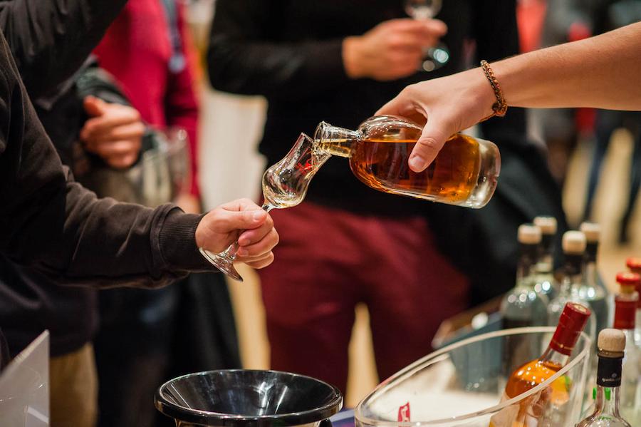 Greek Spirits 2023 - Gastronomy Tours a man holds a glass and a woman pours him a drink from a bottle||