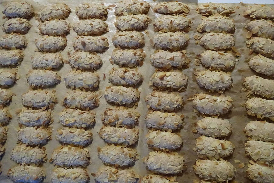 Ergolavos - Gastronomy Tours Close-up of rows of Greek ‘ergolavos’ are sweets crunchy on the outside, soft and chewy in the inside with shelled almonds on top on bakery pan