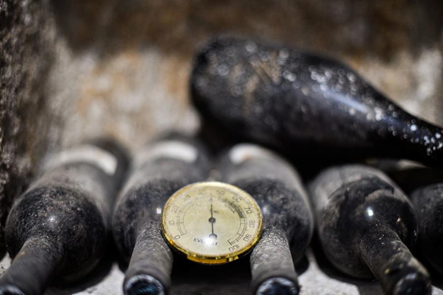 Afianes Wines Awards - Gastronomy Tours close-up of wine bottles with dust on them placed horizontally and a manometer between them at Afianes wines|