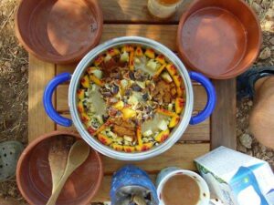 view from above of cooking pot with food like omelet on table and four ceramic bowls with wooden spoons at Korogonas Ark