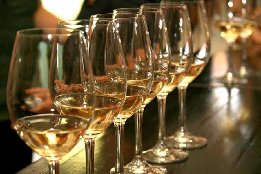 Map of Flavours 2022 - Gastronomy Tours lying glasses of white wine in a row on wooden table at Palivou Estate