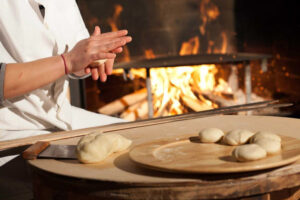 woman making dough at Ktima Perek workshop and a fireplace in the background