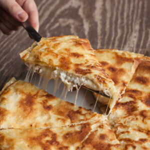 close-up of woman holding a spatula with piece of perek cheese pie at Ktima Perek restaurant