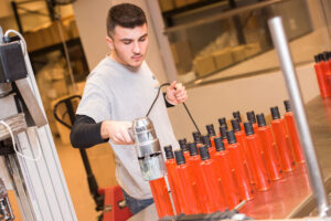 man capping off liqueur bottles with automated system in Lazaris Distillery