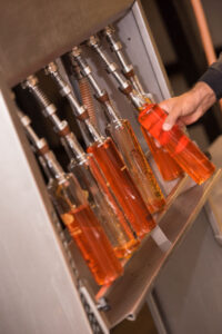 man feeding off liqueur bottles using packaging machine in Lazaris Distillery
