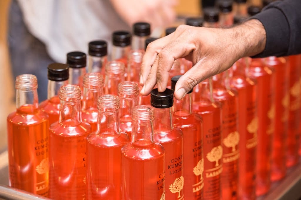 Lazaris Distillery & Artisan Sweets Awards - Gastronomy Tours man capping off liqueur bottles in ‘Lazaris Distillery & Artisan Sweets’ that recognized with many awards|