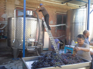 man on the scale on the top of wine tank using hydraulic pump at Liepouris Winery plant