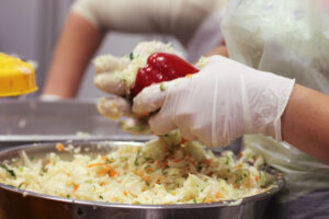 woman with disposable gloves stuffing red pepper with coleslaw at 'Naoumidis All Peppers' plant