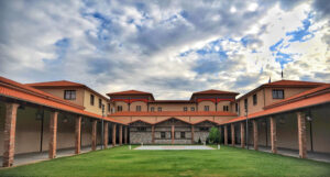 on side of 'Oenogenesis Estate' stone building with columns and green lawn in the front