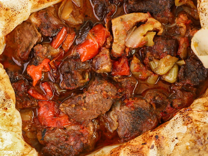 Cooked pieces of &lsquo;Provatina&rsquo;, female lamb meat with peppers, tomatoes and oil in oven