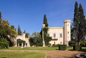 tall towers part of Pyrgos Vasilissis winery surrounded by trees, green lawn and garden
