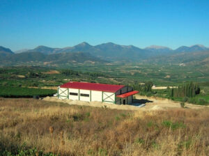 'Wisdom of Nature' industrial building surrounded by trees and dry grass and mountains in the background