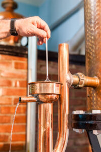 close-up of man holding hydrometer in alcohol at distillery equipment spirits at 'Spentza Distillery