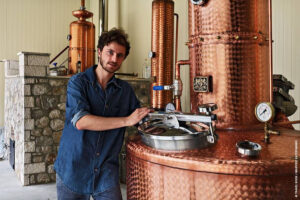 man waching at the camera and he is is by the copper 'Tentoura Castro Distillery'