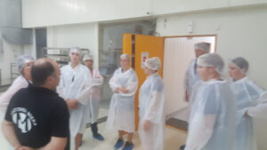 a group of tourists listening to a man giving a tour at 'Bekas Family Farm' plant